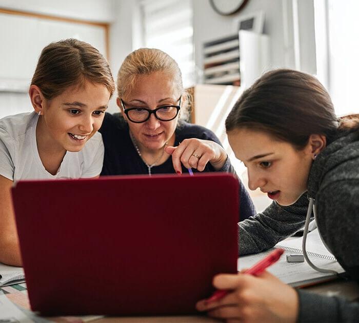 Parent helping two online middle school students on their computer - Connections Academy